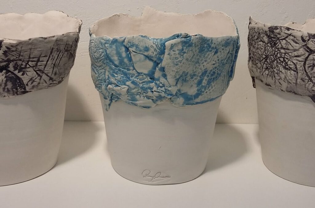 Tre vasi in ceramica bianca con dettagli in azzurro e nero con firma