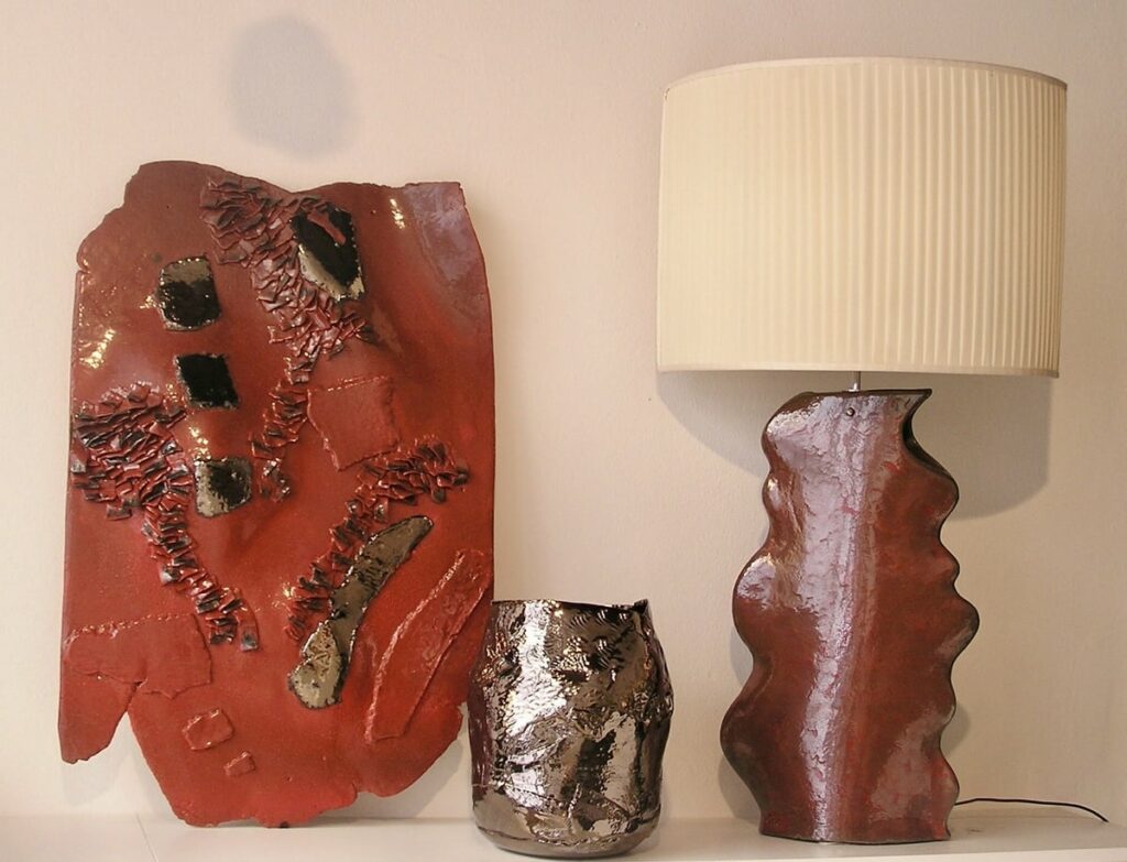 Oggetto da parete rosso e oro, vaso in ceramica lucida e lampada con base in ceramica dal colore rosso intenso